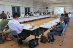 長方形の形で向かい合うようにテーブルを並べ多くの審議員が会議に参加している高砂市総合政策審議会の会議風景の写真