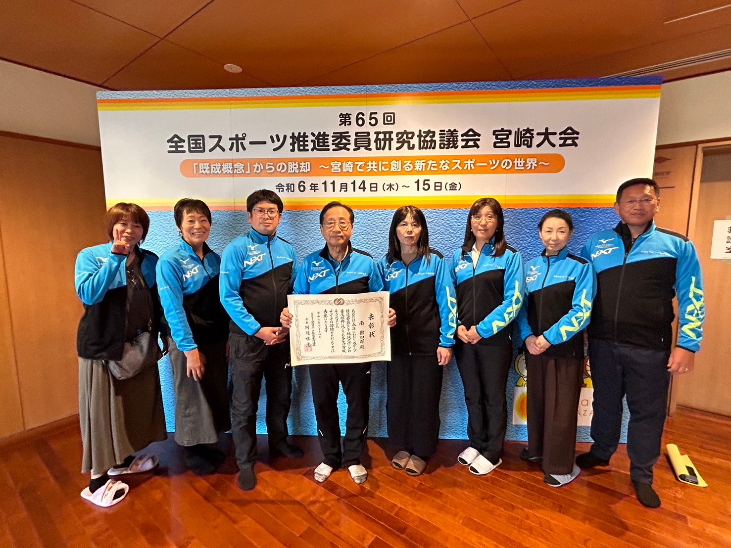 全国スポーツ推進委員研究会宮崎大会の会場で表彰状を手に記念撮影をするスポーツ推進委員の写真