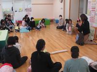 子供達と母親達が円になって座り、話を聞いている写真