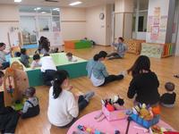 大きな箱の遊具に入って遊ぶ子供達と、その近くで座っている母親達の写真