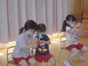 室内に置かれた椅子に座って、ビニール袋の中のいちごを袋越しに手で揉み潰している3人の子供のジャム作りの写真