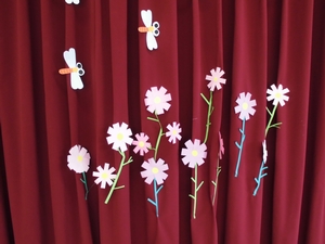 体育館ホールカーテンに飾られているコスモスとアキアカネの切り絵の写真