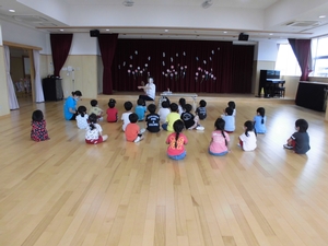 先生の読み聞かせを座って聞くすみれ組の子供たちの写真