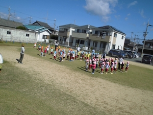 青空の下整列をしてダンスをする子供たちの写真