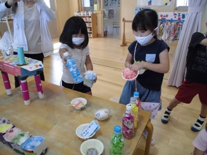 色のついた綿を器に入れてかき氷屋さんごっこをする子供たちの写真