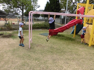 元気よく雲梯で遊んでいる子供と、順番待ちをしている子供たちの写真