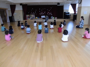 体育館で先生の話を座って聞いているばら組生徒たちの写真