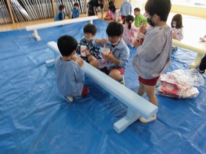 平均台にペンキで色を塗る子供たちの写真
