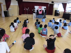 歯のイラストを使って虫歯ができる解説をする講師と、話を聞く子供たちの写真