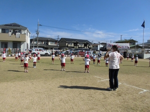 グラウンドで整列して体操をする子供たちの写真
