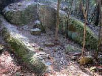 木々の中に苔むした石がある様子が収められた竜山石採石遺跡の写真