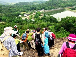 山の岩肌に立って、ため池を眺める参加者たちの写真