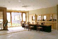陽の光が差し込んだ広い部屋に並ぶ長机と椅子の写真