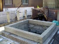 正方形の口から穴が地下まで続いている井戸跡地の写真