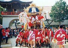 神社のお祭で20人くらいの人がみこしを担いでいる様子の写真