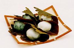 2つの草色と3つの白色の柏餅が重ねて盛り付けられてた美味しそうな写真