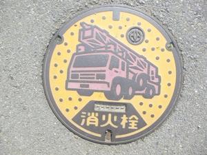 アスファルトの地面に設置された丸型消火栓の写真