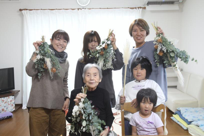 手作りのリースをそれぞれの手に持って微笑むご家族