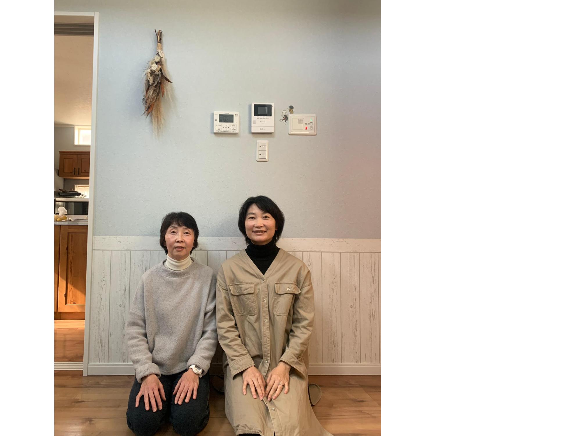 白い壁の前でフローリングの上に正座で座るふたりの女性