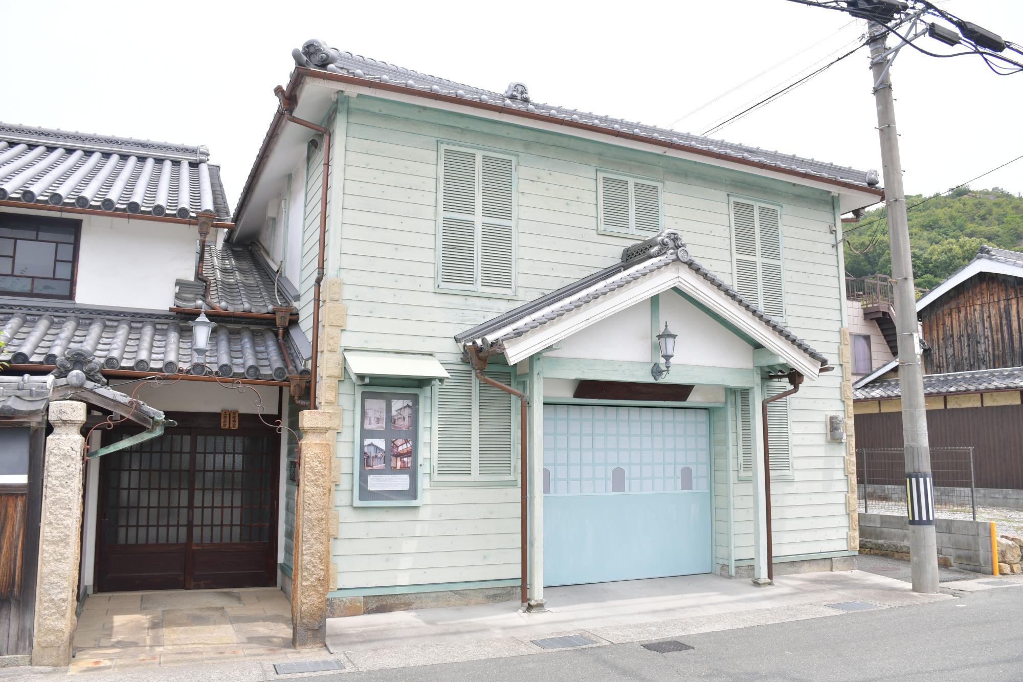 ミントグリーンに塗装された板壁で出来た洋風建築の旧魚橋郵便局外観の写真