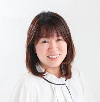 白いスーツ姿で正面を向いている笑顔の井口佳永子議員の写真