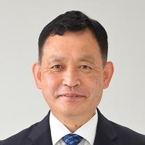 黒いスーツ姿で正面を向いている笑顔の春増勝利議員の写真