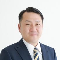 黒いスーツ姿で正面を向いている笑顔の松野優也議員の写真