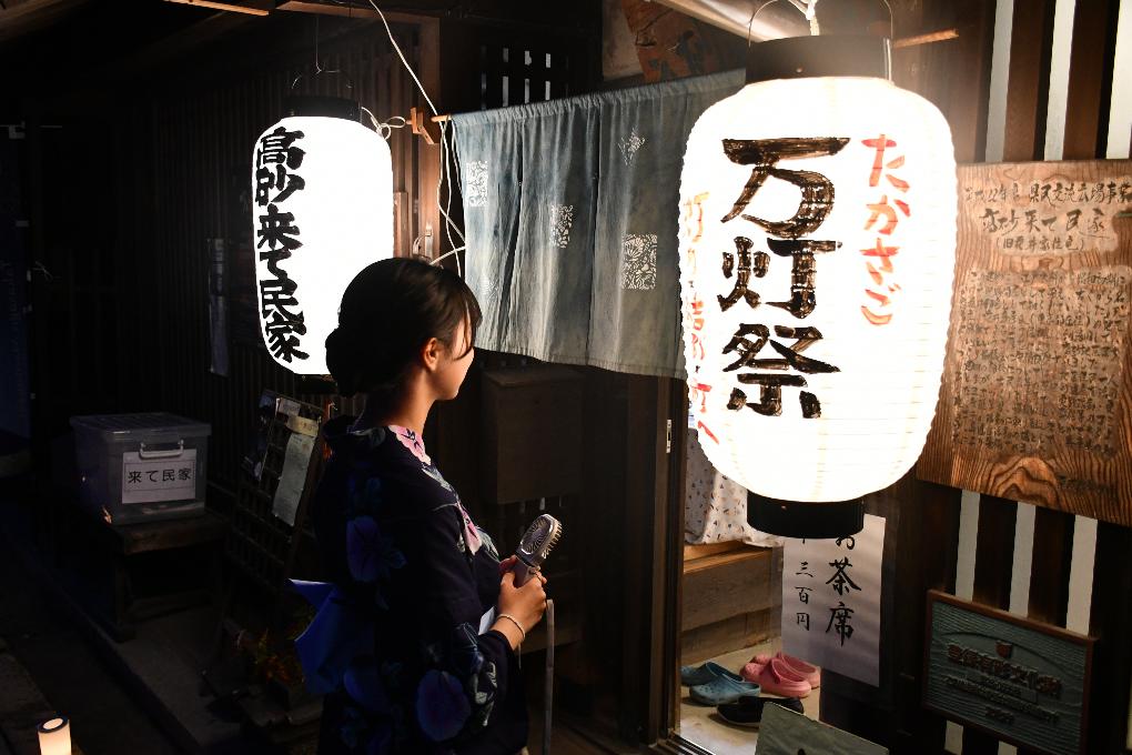 古民家の玄関先で「高砂万灯祭」と書かれてある大きな提灯の前にたたずむ浴衣姿の女性の写真