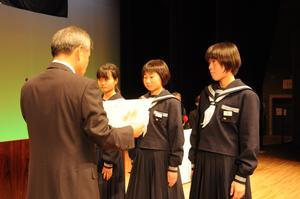 制服を着た女学生達が白髪の男性から賞状を受け取っている写真