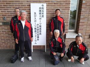 令和元年度兵庫県スポーツ推進委員中央研究協議会と書かれた看板の横で記念撮影するスポーツ推進委員の写真