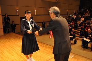 制服を着た女学生が白髪の男性から賞状を受け取っている写真