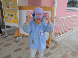 各側面に色を塗ったペットボトルを覗き込んでこちらを見る男の子の写真