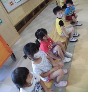 木製の子供用ベンチに座りながら歯科検診の順番待ちをする子供たちの写真
