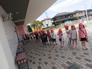 ピンクの帽子をかぶって笑顔で並ぶ子供たちの写真
