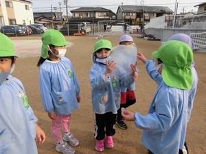 水たまりで出来た大きな丸い氷を掲げる子供たちの写真