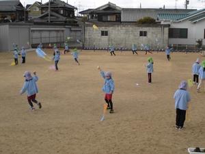 色とりどりのビニール紙で作られた手作り凧を飛ばす園児たちの写真