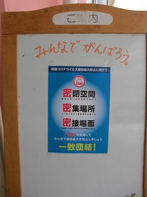 手書きで書かれた「みんなでがんばろう。」の文字の下に三密予防のポスターが貼られている写真