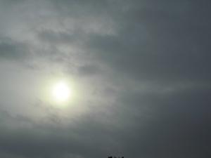 おぼろ雲がかかってぼんやりと光っている太陽と空の写真