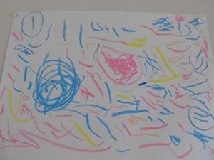 ピンクと青の線を背景に、自由なタッチで描かれている園児の描いたプリキュアの写真