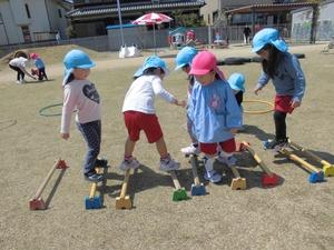 園児たちがハードルの上でバランスを取りながら立ったり歩いたりしている写真