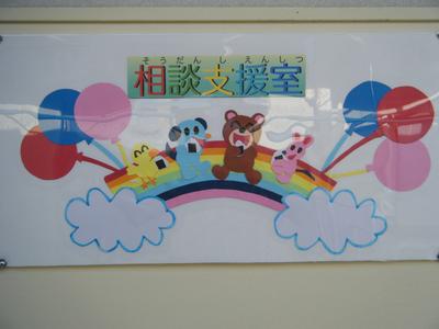 くま、うさぎ、ひよこ、いぬの4匹の動物が虹の上で笑っているイラストの上に「相談支援室」とかかれた看板の写真