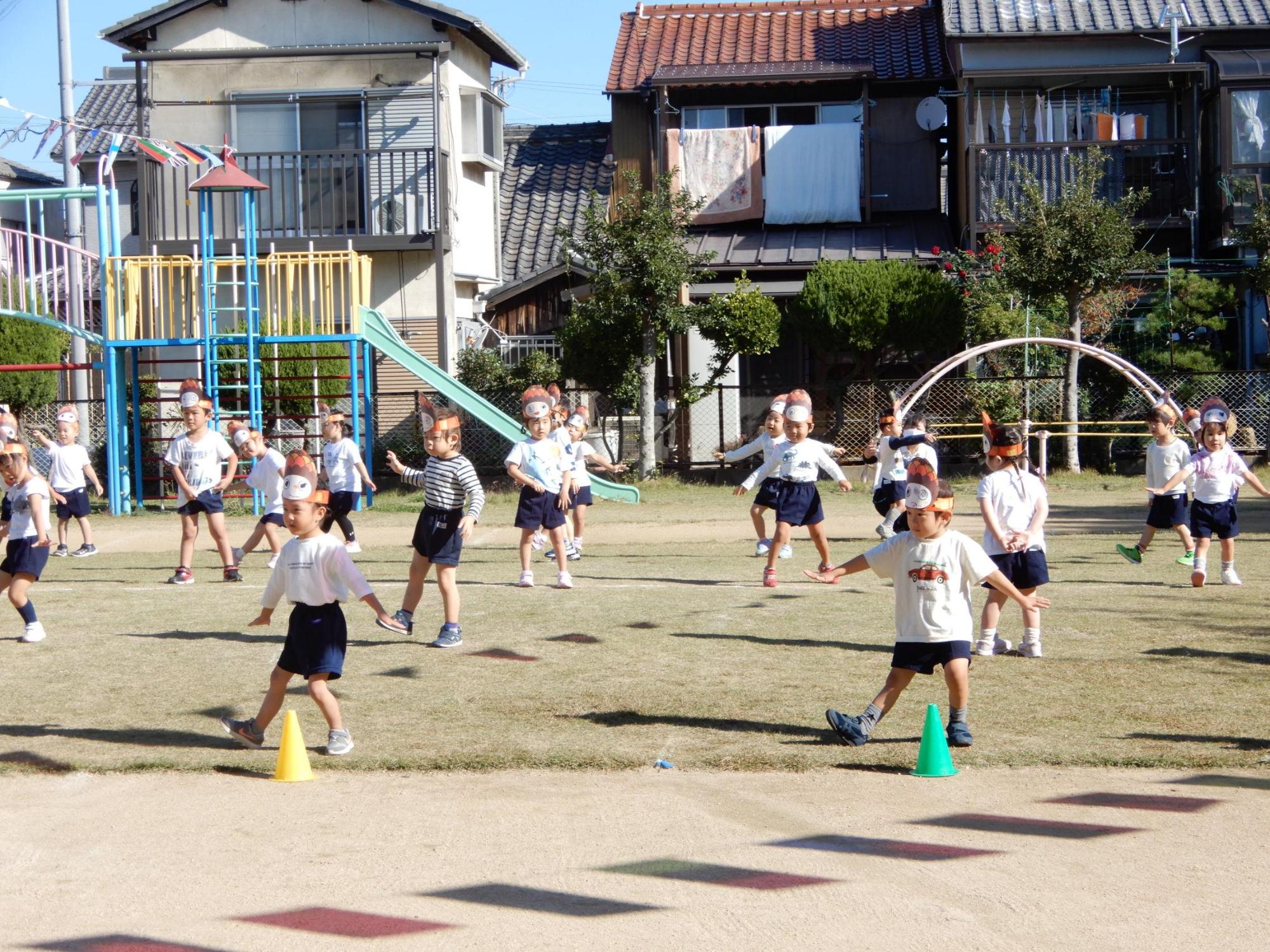 園庭でおこなわれた運動会で頭に面を付けて踊る3歳児クラスの園児たちの写真