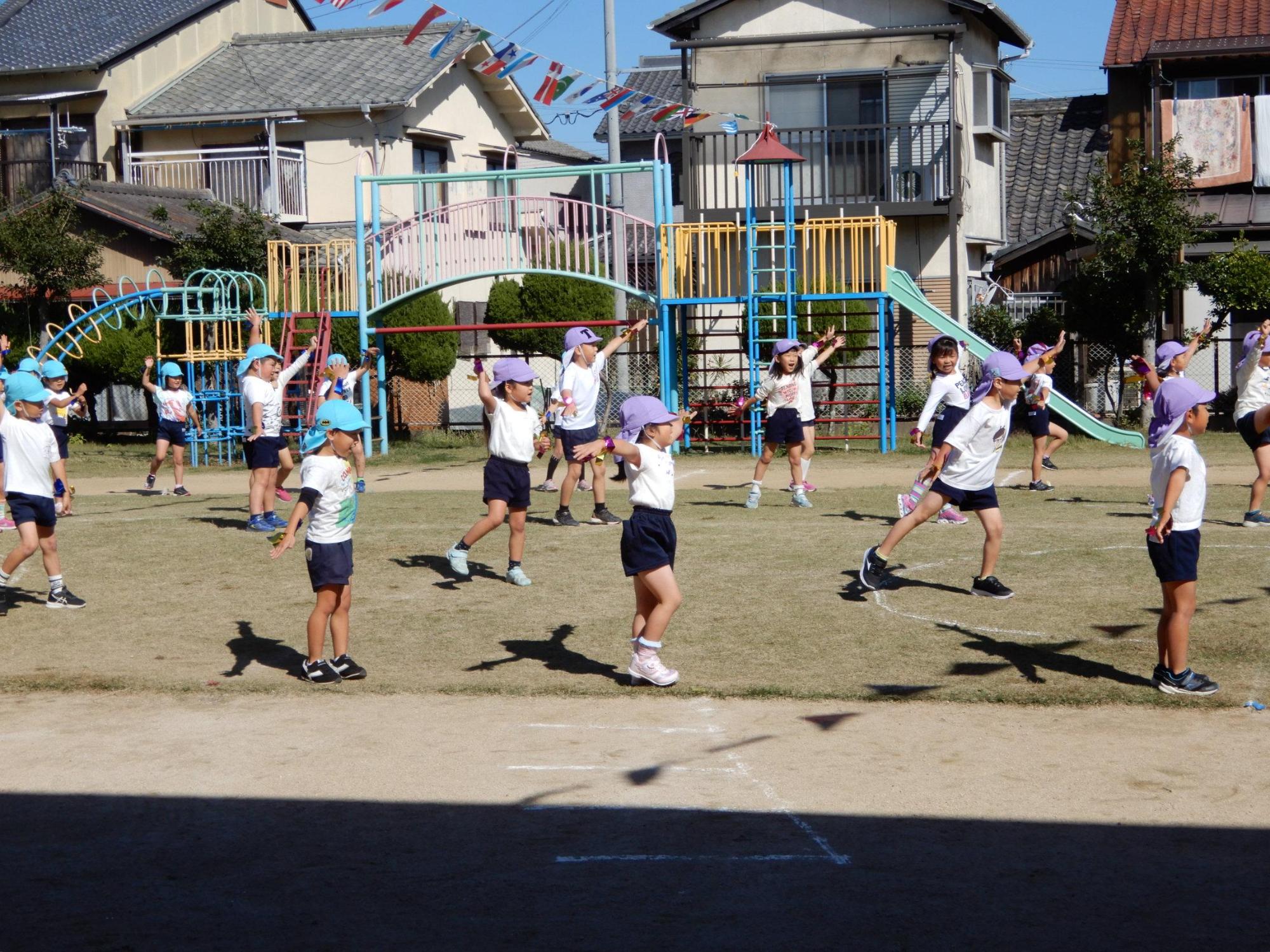 等間隔に並びながら体操をする5歳児クラスの園児たちを右横から撮影した写真