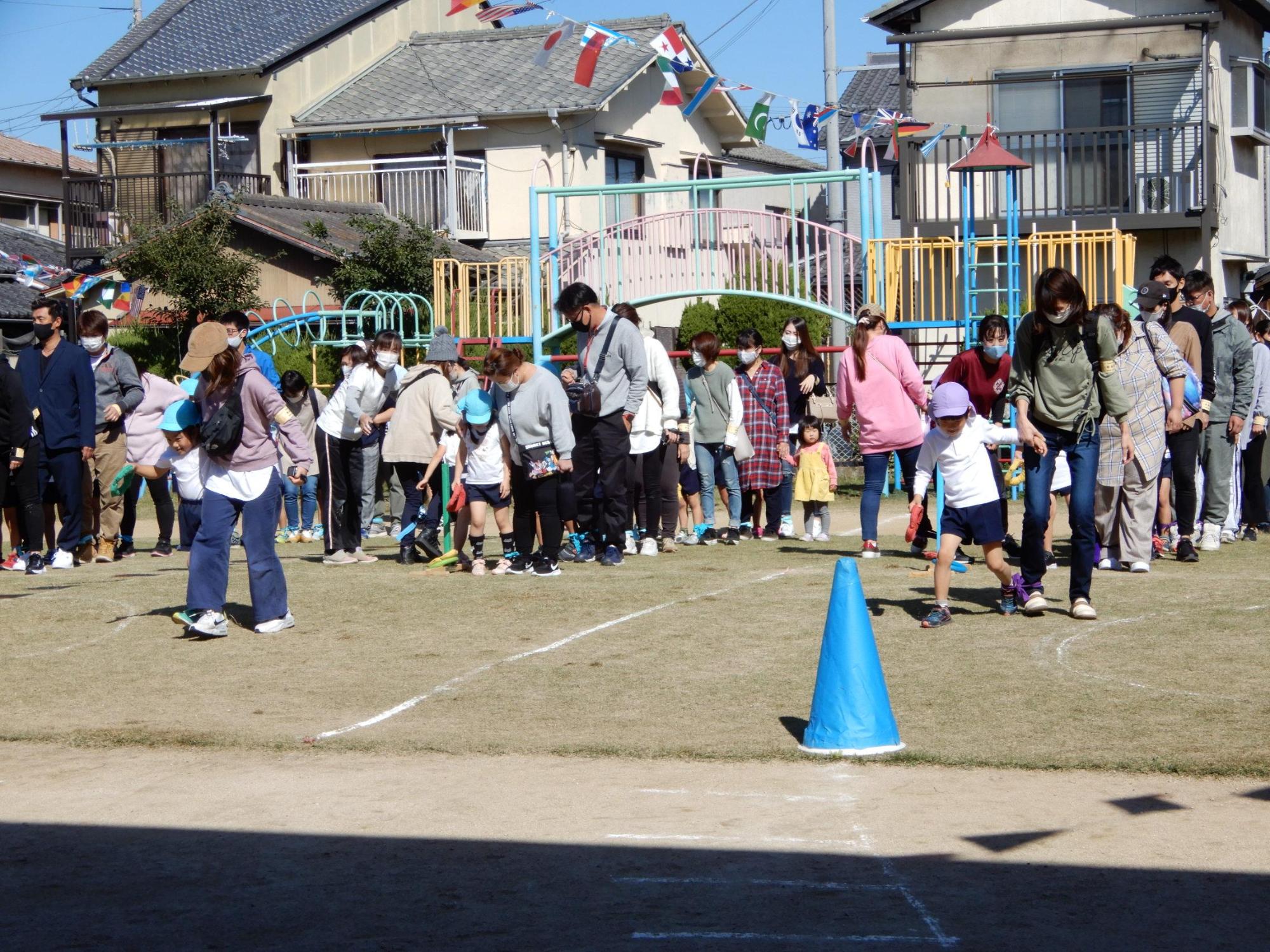 悪戦苦闘しながら保護者と二人三脚をする5歳児クラスの園児たちの写真