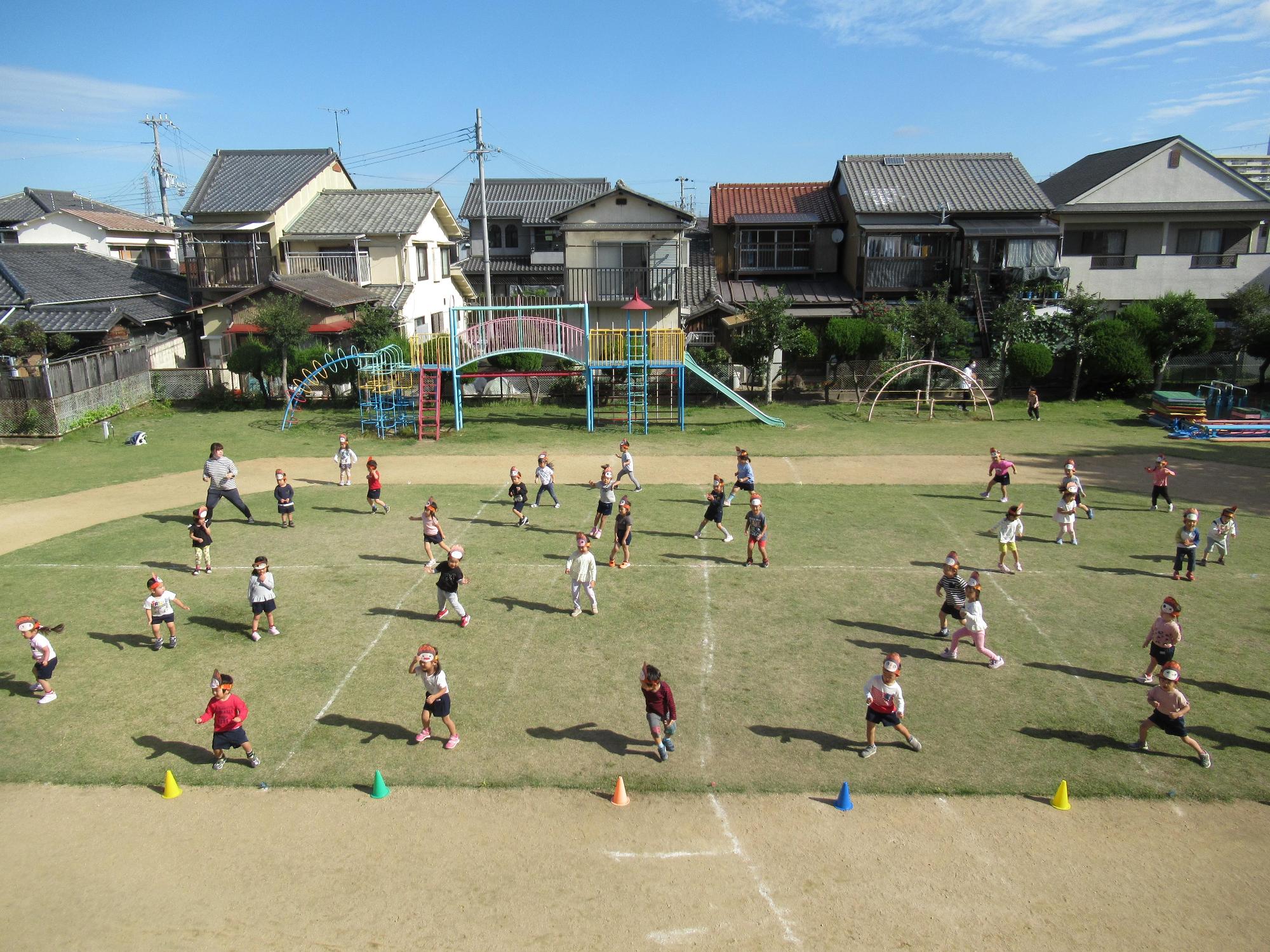 先生たちと一緒にぼっくりんダンスをする園児たちを上空から撮影した写真