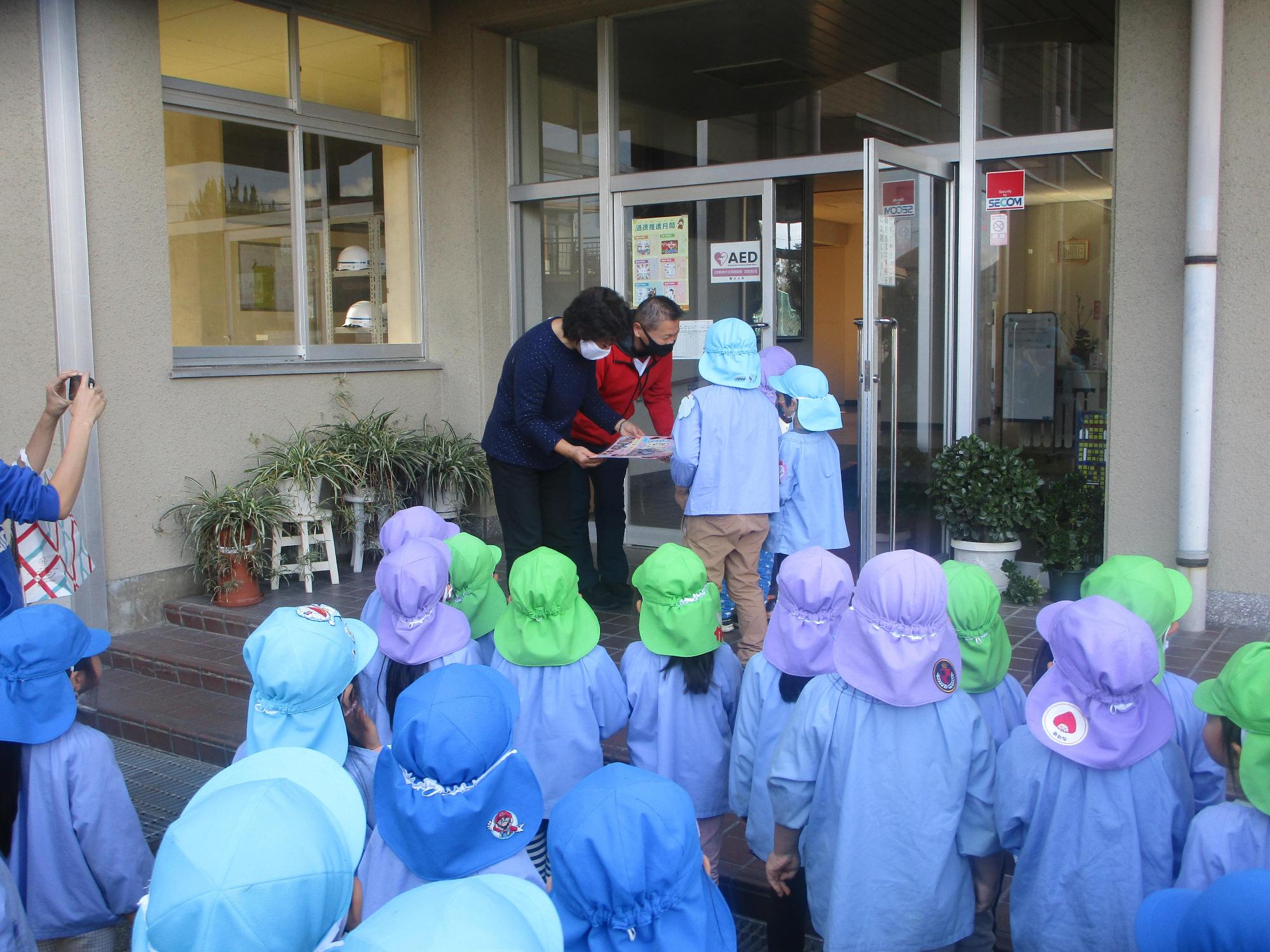 高砂中学校の校舎の入口前階段付近に保育園児たちが集まり、高砂中学校の関係者にお礼の挨拶をしている様子の写真