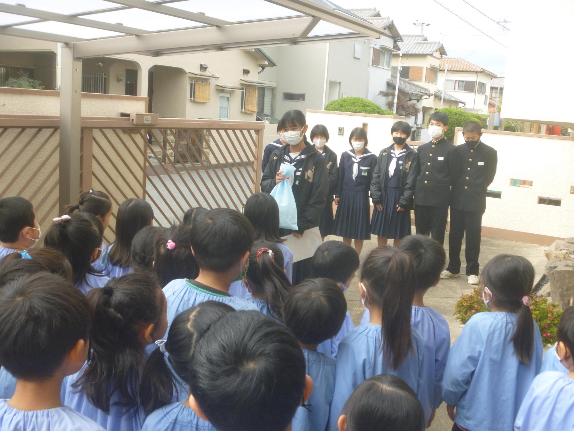 高砂中学校2年生の男女数名が対面した保育園児たちに手作りのマスクを渡している様子の写真