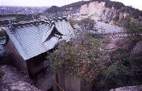 宝殿山中腹地点より俯瞰で撮影された、生石神社本殿の背面と石の宝殿の写真。写真の奥には竜山の遠景も確認できる