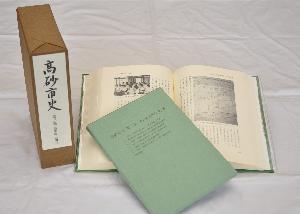 高砂市史第三巻「通史編 近現代」のサンプル写真。直立した函、見開きになったハードカバーの本、更にその本の上に付図がで配置されている