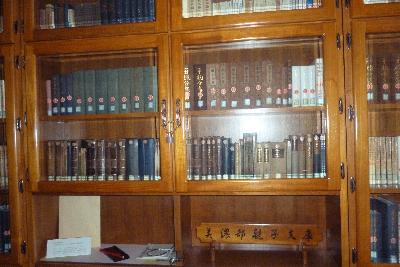 たくさんの書籍が木造りでガラス扉のついた年代物の書棚に収められている写真